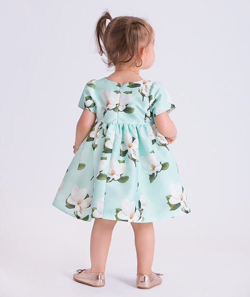 Baby girl wearing a mint floral dress with flower appliqué detail by Mama Luma